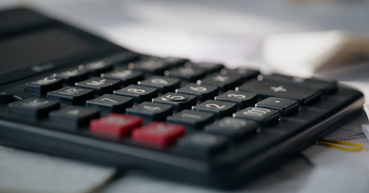 Close-up of a black desktop calculator on a desk with papers